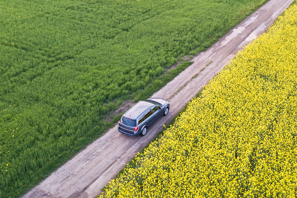 Aerial view of a silver SUV driving on a dirt road - https://www.richardgreeninsurance.com/